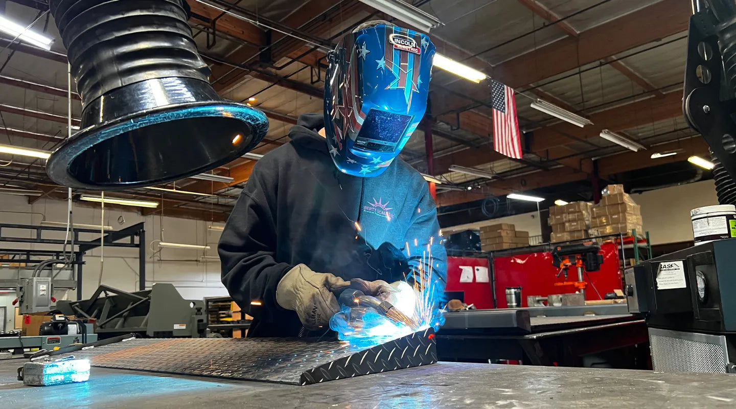 Person welding metal in a factory setting | Liberty Scales USA Made Floor Scales